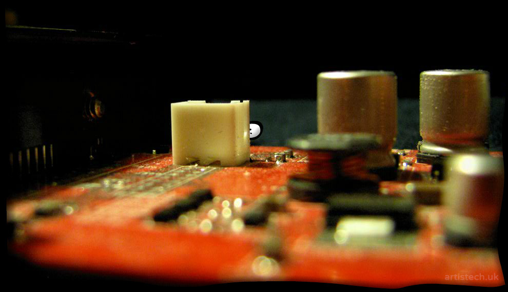 Cartoon figure peeking from behind a component on an old computer board 